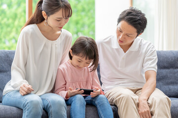 ソファーに座ってスマートフォンを使う親子