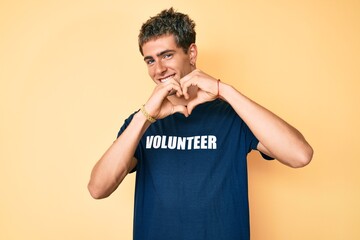 Young handsome man wearing volunteer t shirt smiling in love doing heart symbol shape with hands. romantic concept.