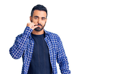 Young hispanic man wearing casual clothes mouth and lips shut as zip with fingers. secret and...