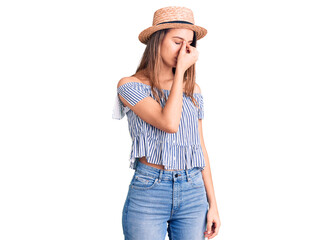 Young beautiful girl wearing hat and t shirt tired rubbing nose and eyes feeling fatigue and headache. stress and frustration concept.