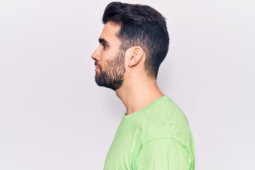 Young handsome man with beard wearing casual t-shirt looking to side, relax profile pose with natural face with confident smile.