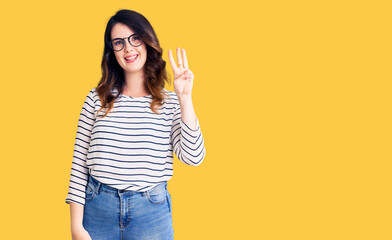 Beautiful young brunette woman wearing casual clothes and glasses showing and pointing up with fingers number three while smiling confident and happy.