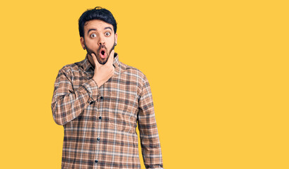 Young hispanic man wearing casual clothes looking fascinated with disbelief, surprise and amazed expression with hands on chin