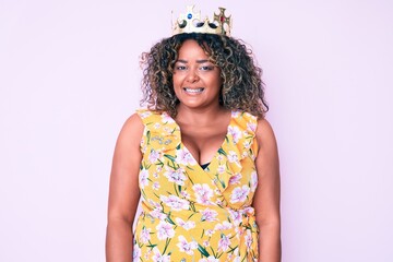 Young african american plus size woman wearing princess crown with a happy and cool smile on face....