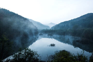 Beautiful autumn scenery, water mist over the lake and sea clouds on the mountain at dawm.