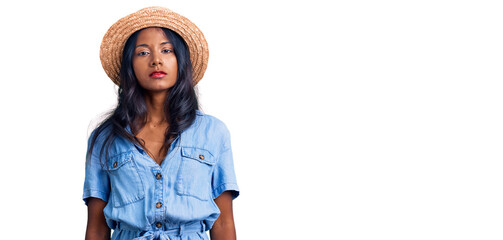 Young indian girl wearing summer hat relaxed with serious expression on face. simple and natural...