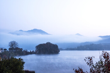 Beautiful autumn scenery, water mist over the lake and sea clouds on the mountain at dawn.