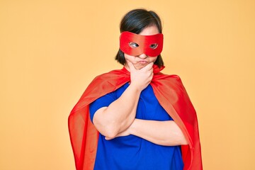 Brunette woman with down syndrome wearing super hero costume thinking looking tired and bored with depression problems with crossed arms.
