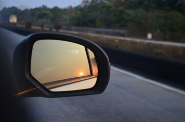 Sunset reflection on mirror during travel on highway.