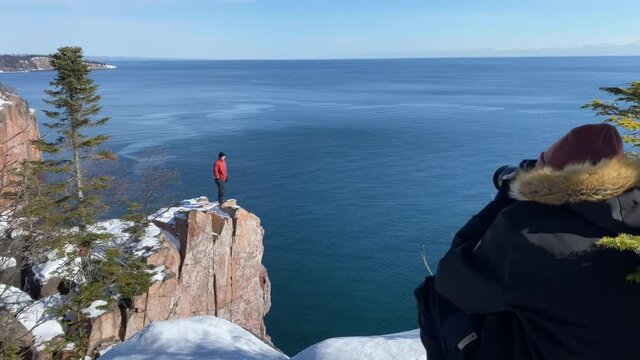 guy taking pictures of another guy at palisade head at lake superior tettegouche state park during winter time