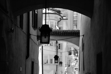three antique lamps hang in narrow lane in the old town of Bolzano, South Tirol. Monochrome