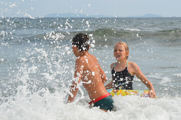 Caucasian children outdoor on the beach in summer lifestyle swim in the sea