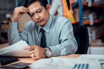 Stressed businessman worry about financial balance trouble of his company at his office in...