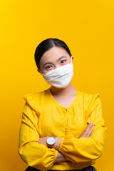 Asian woman wearing protective face mask isolated on yellow background.