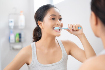 Beautiful female brushing teeth in the bathroom