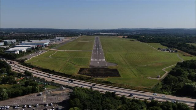 Southampton International Airport Runway aerial drone shot. UK flights, transportation. COVID-19 means lack of flights, quiet. Flybe job losses. Airfield, coming in to land. Zoom