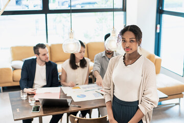 オフィスでポーズをするビジネスウーマンと国際色豊かなビジネスチーム