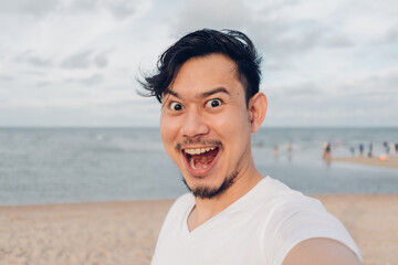 Happy Asian man selfie himself while walking on the beach.
