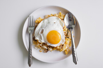 Homemade fried rice with fried egg on top served on white dish.