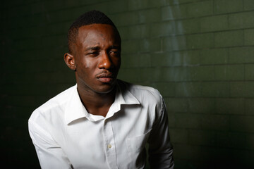 Young African businessman against brick wall in the dark