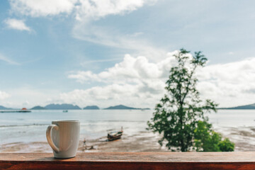 Morning coffee mug with low tide sea view as background.