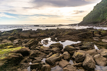 Beautiful beach rocks with sunset and calm cloudy sky.