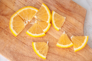 An orange cut into slices is lying on a wooden Board on the table