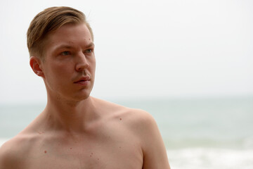 Young handsome shirtless tourist man relaxing at the beach