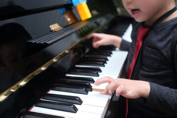 Little Asian kid boy playing piano in living room at home, Preschool child having fun with learning to play music instrument, Music education concept, Soft and selective focus © yAOinLoVE