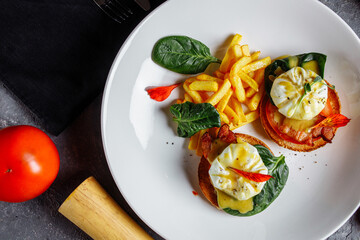 Poached eggs with french fries and bacon on toast