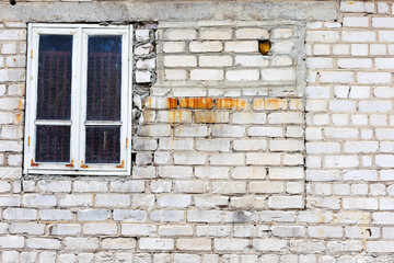 Fototapeta na wymiar Old window in a brick wall of white brick with cracks and scratches. Landscape style. Great background or texture.