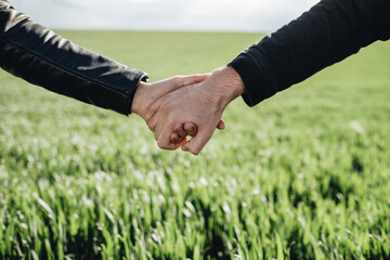 Happy Young Couple Holding Hands in the Green Field