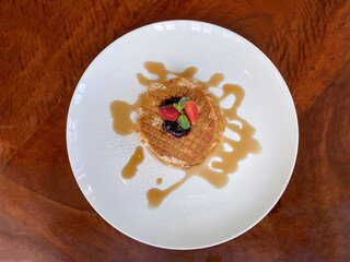 Fresh pan cakes with blueberry jam maple syrup strawberry topping on white plate rustic brown table