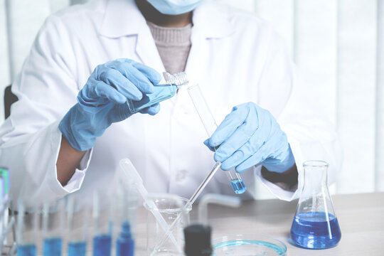 Scientists hold a glass tube filled with blue chemical liquid for research and analysis in a laboratory