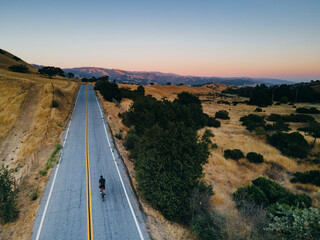 Obraz premium Solo bike rider on straight country road, drone aerial