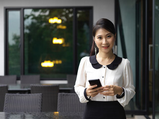 Fototapeta na wymiar Portrait of smiling businesswoman using smartphone in cafeteria