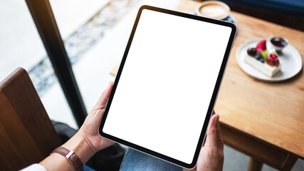 Mockup image of a woman holding digital tablet with blank white desktop screen in cafe