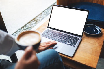 Top view mockup image of a woman using and touching on laptop touchpad with blank white desktop screen while drinking coffee