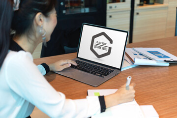 Side view of businesswoman working on mock up laptop on meeting table