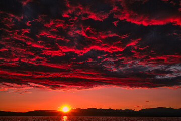 Dark red sunset on the beach and sea. Vintage Filter. Sunrise over the sea. Dark red clouds with...