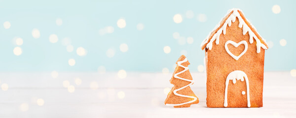 Homemade gingerbread house scene on warm blue bokeh background, Merry Christmas, Happy New Year congratulations banner, copy space, flyer, post card, voucher, coupon