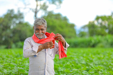 Happy Indian farmer at green cotton field