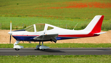 Fototapeta na wymiar Sport airplane taking up from runway on airfield on summer day.