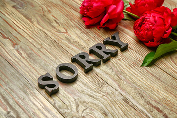 Flowers with word SORRY on wooden background
