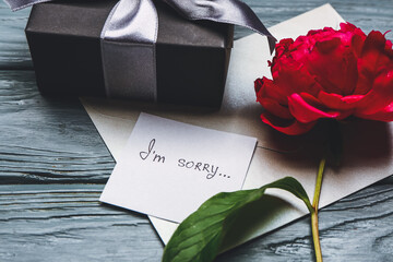Gift box and letter with text I'M SORRY on wooden background