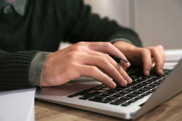 Young man using laptop for online learning at home, closeup