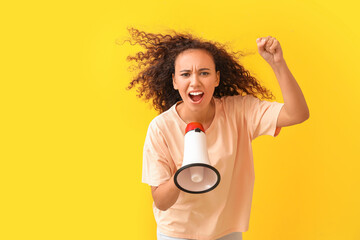 Angry protesting African-American woman with megaphone on color background