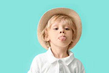Cute little boy showing tongue on color background