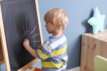 Cute little boy drawing in kindergarten