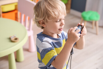 Cute little boy playing with photo camera at home